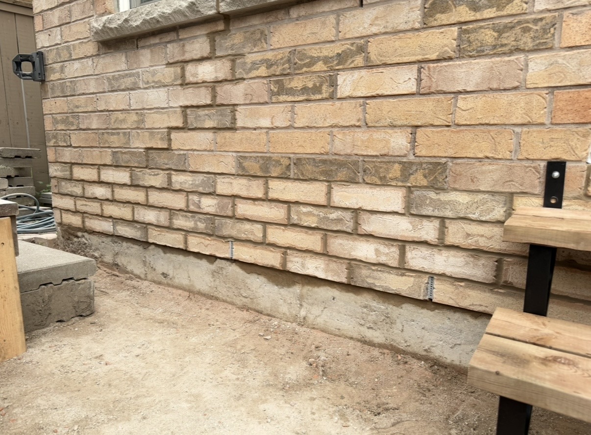Lower brick course being repaired along a house wall