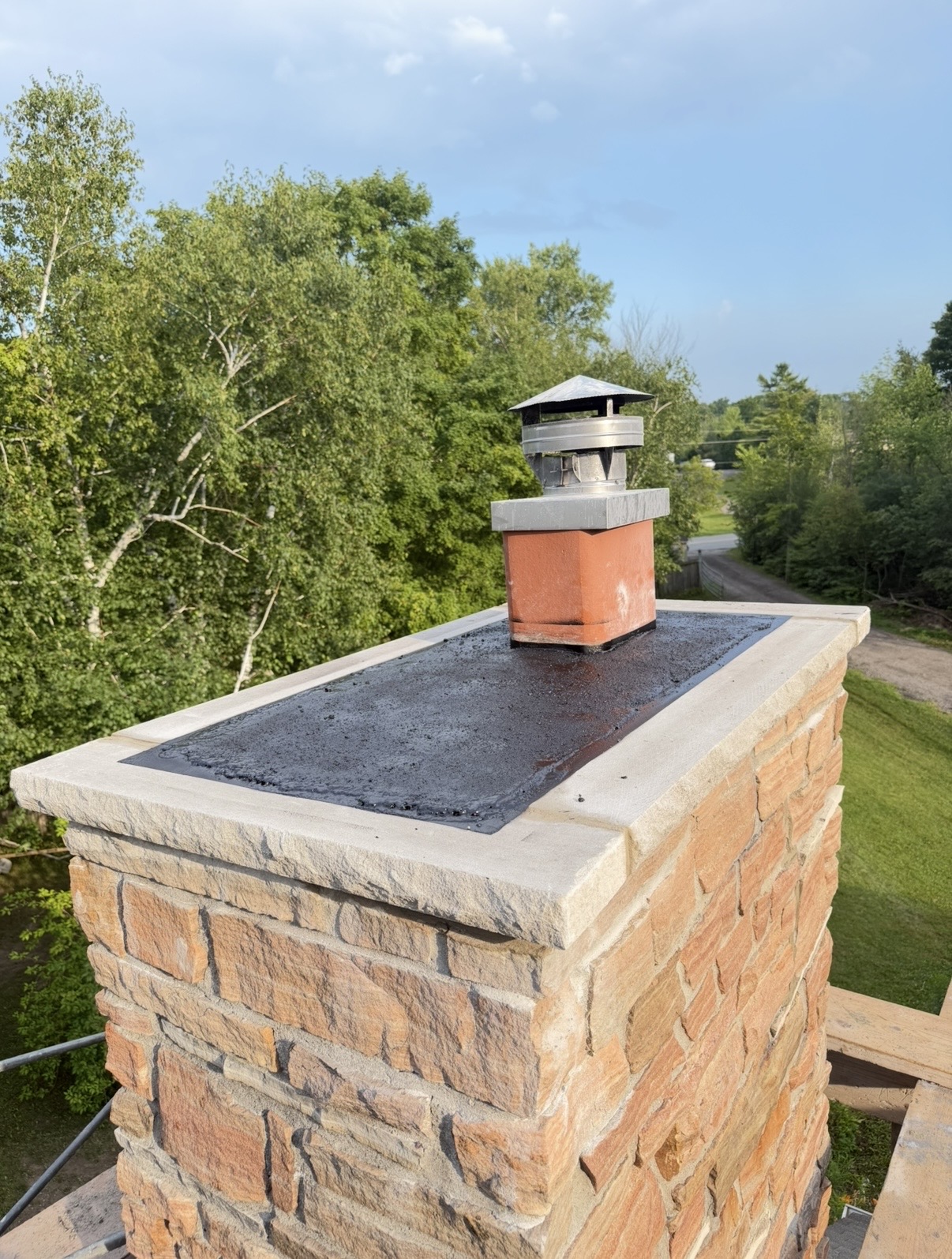 Stone Chimney Crown — Stone chimney with a finished crown, sealed surface and new cap.