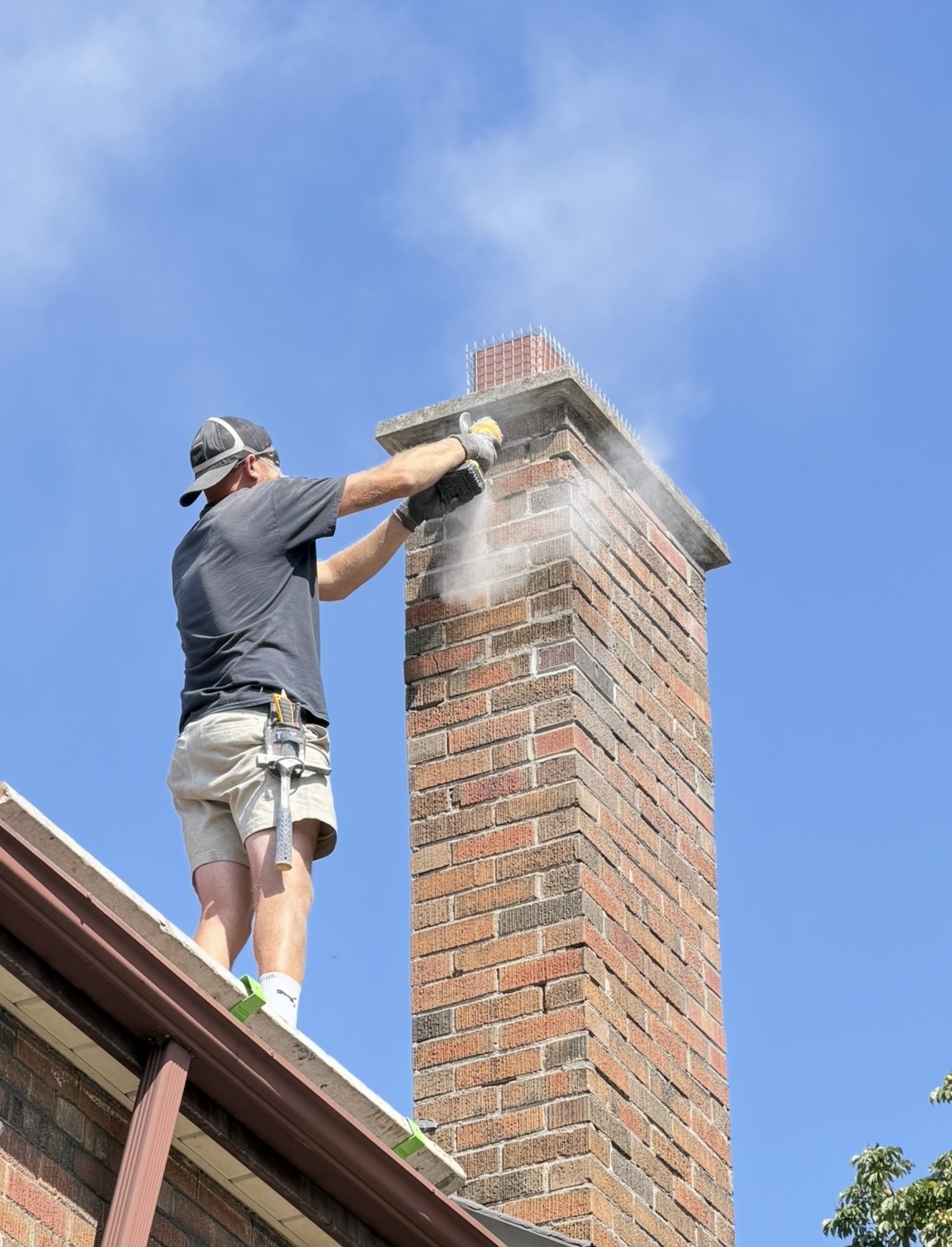 Mason grinding out old mortar joints on a brick chimney